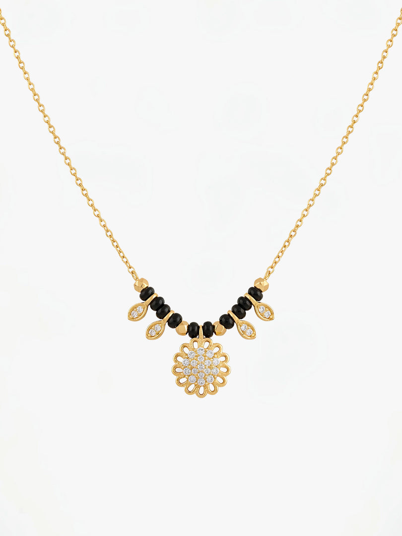Gold necklace with black and white beads on a white background
