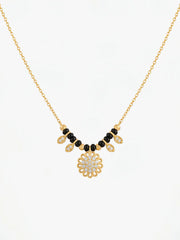Gold necklace with black and white beads on a white background