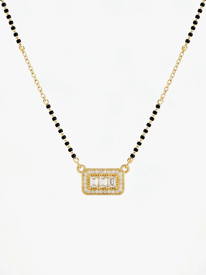 Gold necklace with black beads and a rectangular pendant on a white background