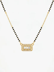 Gold necklace with black beads and a rectangular pendant on a white background