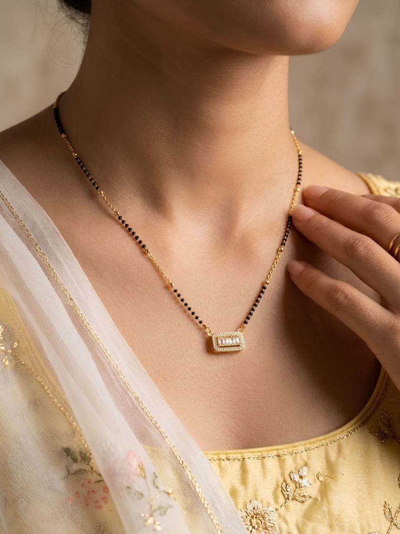 Woman wearing a gold necklace with a pendant, dressed in a traditional outfit.