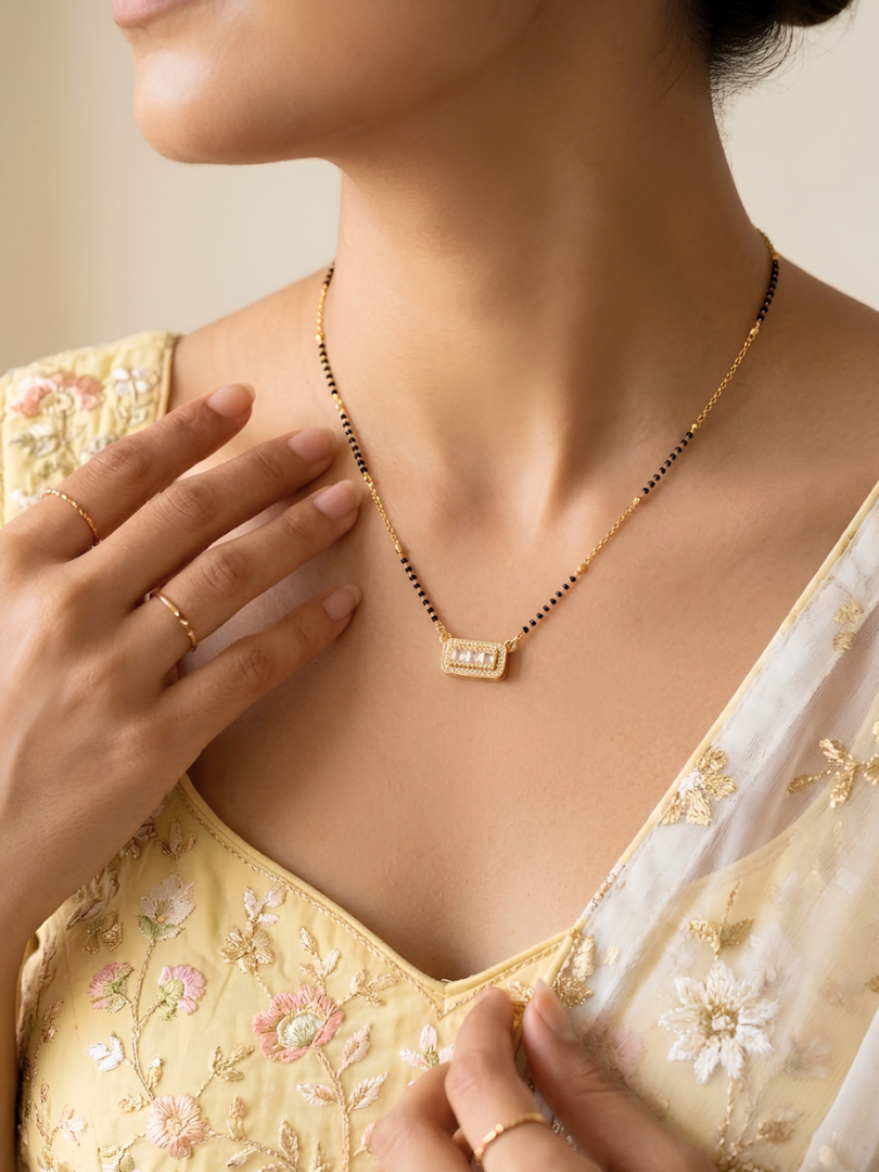 Woman wearing a gold necklace with a close-up of the necklace and part of her outfit.