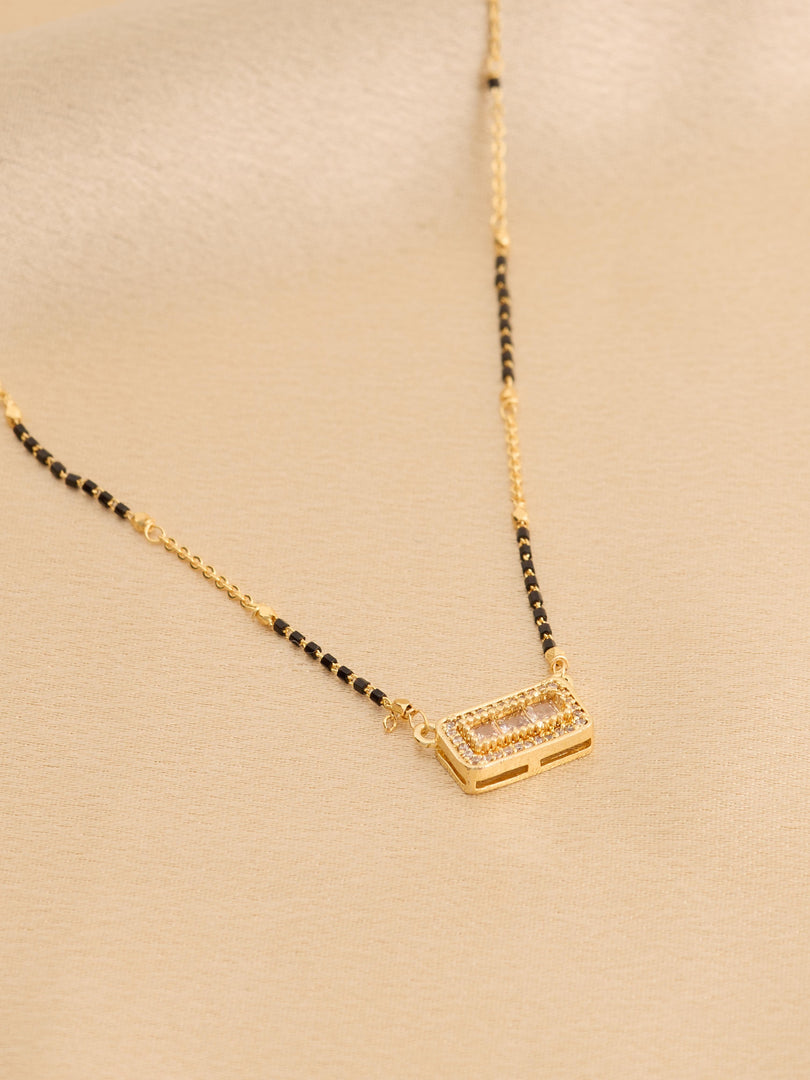 Gold necklace with black beads on a beige background