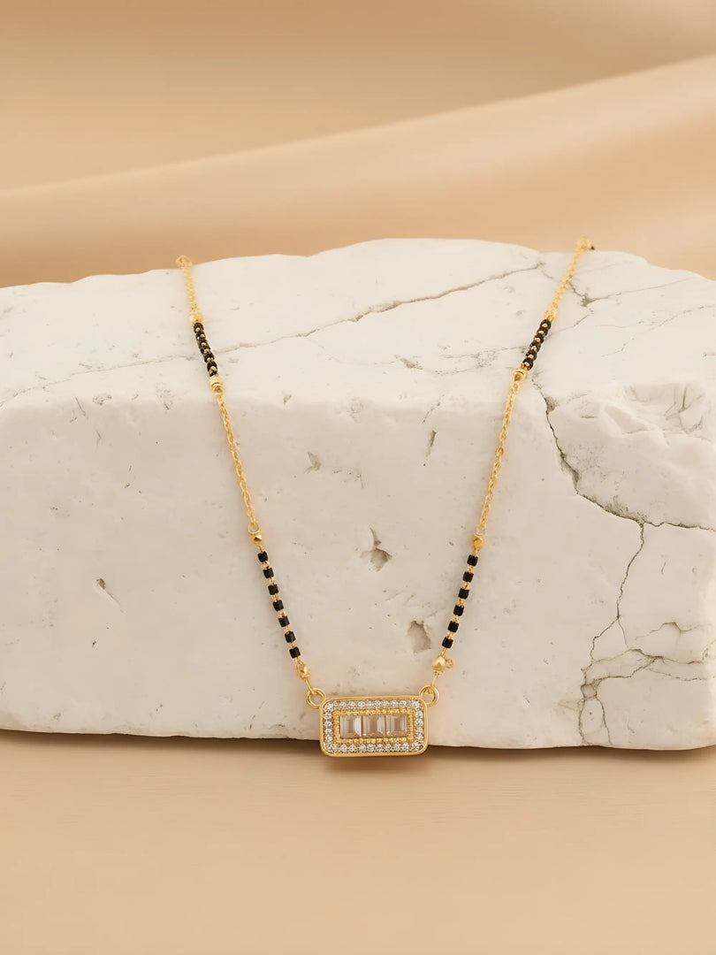 Gold necklace with black beads on a marble surface