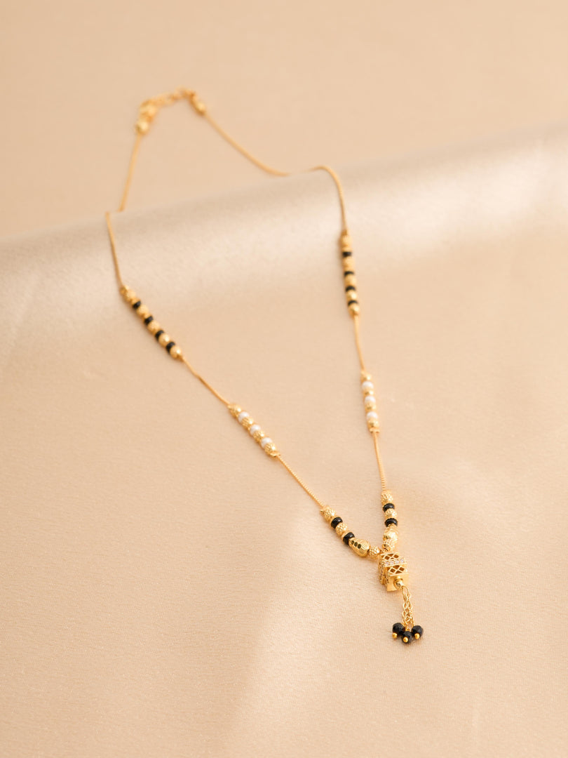 Gold necklace with black beads on a beige background