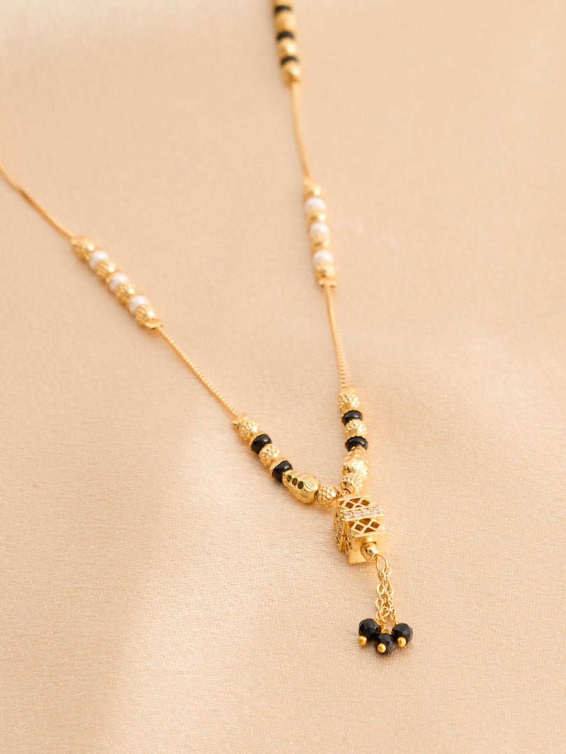 Gold necklace with black beads on a beige background