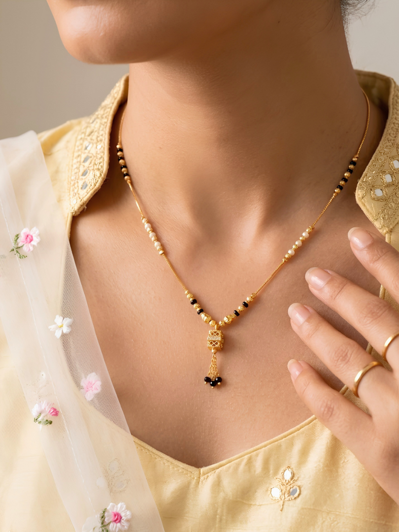 Woman wearing a gold necklace with a delicate pendant, close-up of the neck and chest area.